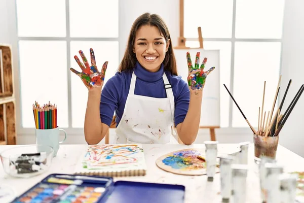 在艺术工作室里 年轻的黑发女人 手绘着彩绘 用9号指尖 面带微笑 自信而快乐 — 图库照片