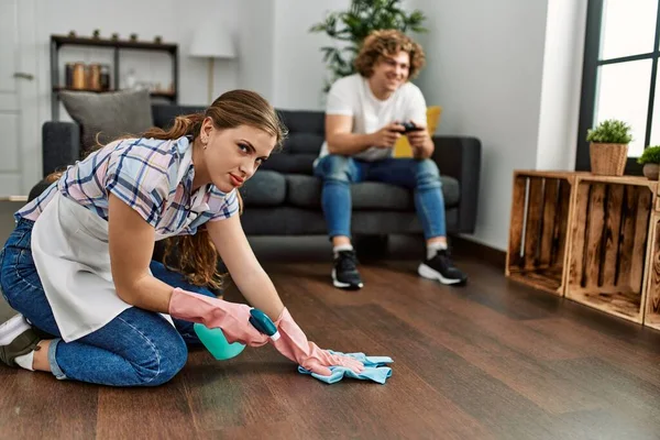 Kobieta Sprzątanie Domu Podczas Gdy Mężczyzna Gra Gry Wideo Domu — Zdjęcie stockowe