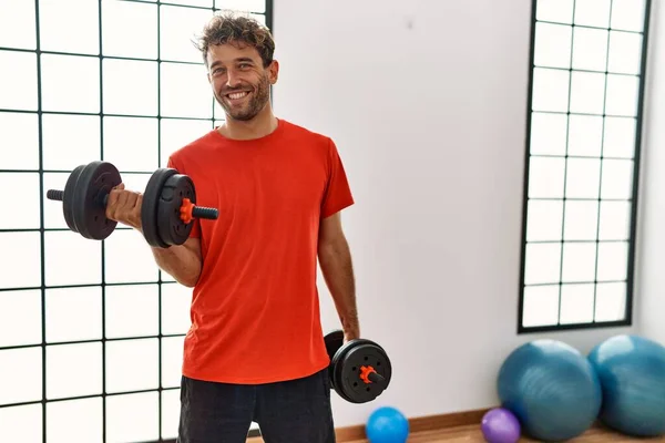 Giovane Uomo Ispanico Sorridente Allenamento Fiducioso Utilizzando Manubri Centro Sportivo — Foto Stock