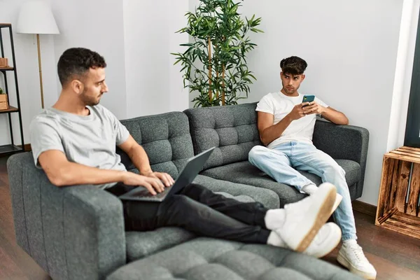 Two Hispanic Men Couple Disagreement Using Smartphone Laptop Home — Stockfoto