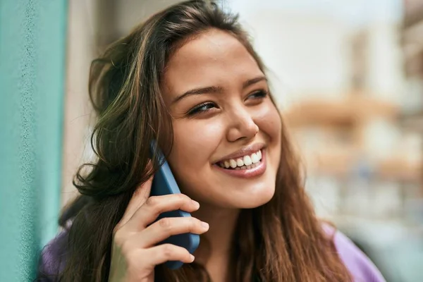 若いヒスパニック系の女性は 市内のスマートフォンで幸せな話を笑って — ストック写真