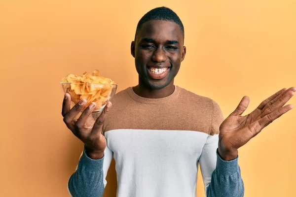 Young African American Man Holding Bowl Potato Chip Celebrating Achievement — Stock Photo, Image