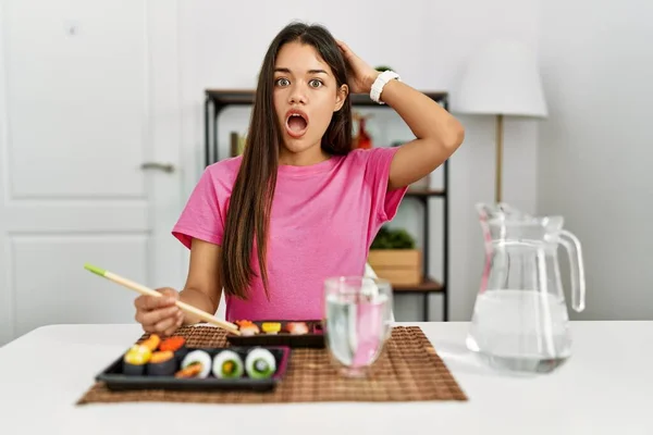 若いですブルネット女性食べる寿司箸クレイジーと恐怖で手で頭 恐怖と驚きのショックでオープン口 — ストック写真