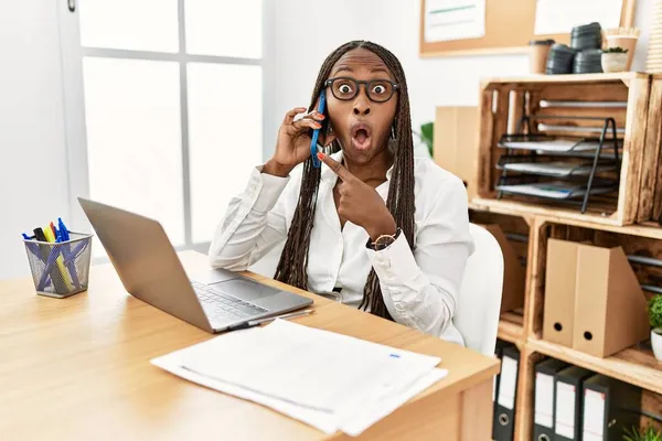 Mulher Negra Com Tranças Trabalhando Escritório Falando Telefone Surpreso Apontando — Fotografia de Stock