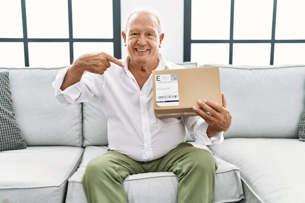 Starší Muž Který Doma Drží Doručovací Balíček Ukazuje Prstem Jednoho — Stock fotografie