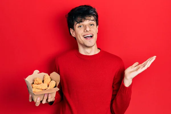 Bonito Jovem Hipster Comendo Asas Frango Celebrando Realização Com Sorriso — Fotografia de Stock