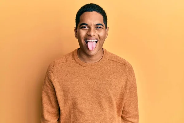 stock image Young handsome hispanic man wearing casual winter sweater sticking tongue out happy with funny expression. emotion concept. 