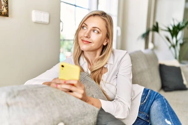 Mujer Rubia Joven Usando Teléfono Inteligente Sentado Sofá Casa — Foto de Stock