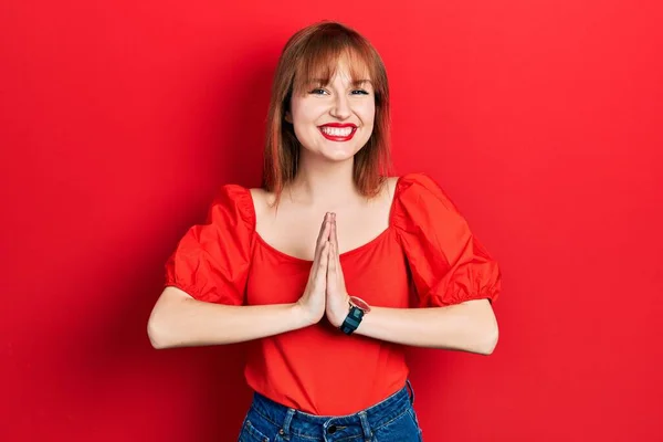 赤いTシャツを着た若い女性が手で祈っている一緒に笑顔を許しを求めて自信を持って — ストック写真