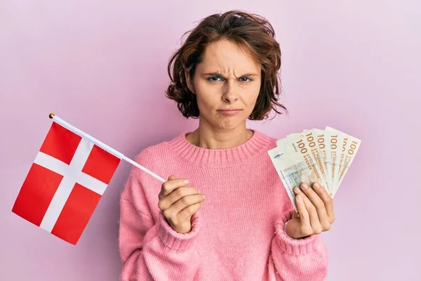 ノルウェー国旗を掲揚する若いブルネットの女性は 銀行券を懐疑的で緊張し 問題のために動揺して眉をひそめています 否定的な人 — ストック写真