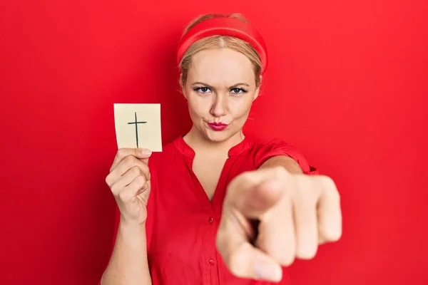Young Blonde Woman Holding Catholic Cross Reminder Pointing Finger Camera — Photo