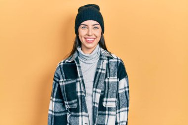 Mavi gözlü, yünlü şapkalı, yüzünde mutlu ve havalı bir gülümseme olan güzel bir kadın. şanslı kişi. 