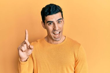 Yakışıklı, sıradan kıyafetler giyen, bir fikri olan ya da soru soran mutlu bir yüzü olan yakışıklı bir adam. 