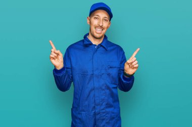 Bald man with beard wearing builder jumpsuit uniform smiling confident pointing with fingers to different directions. copy space for advertisement 