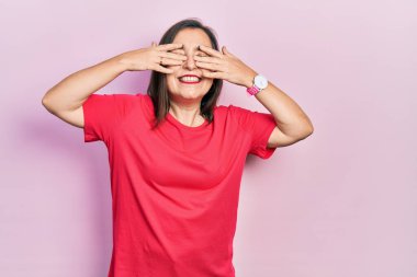Orta yaşlı İspanyol kadın gündelik kıyafetler giyiyor. Gözleri kapatıyordu. Neşeli ve komik gülümsüyordu. kör kavram. 