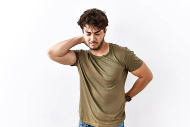 Hispanic man standing over isolated white background suffering of neck ache injury, touching neck with hand, muscular pain 