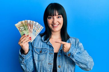 Genç İspanyol kadın Peru banknotları tutuyor. Gülümsüyor, mutlu bir şekilde parmakla işaret ediyor. 