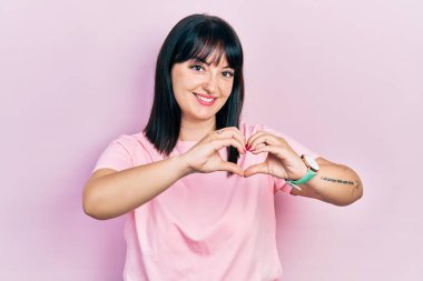 Gündelik kıyafetler giyen, aşık gülümseyen, elleriyle kalp sembolü yapan genç İspanyol kadın. romantik kavram. 