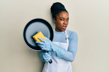 Saçları örgülü, önlük takan, şok olmuş suratında çamaşır kabı olan, şüpheci ve alaycı bakışlı, ağzı açık bir şekilde şaşırmış Afro-Amerikan bir kadın. 