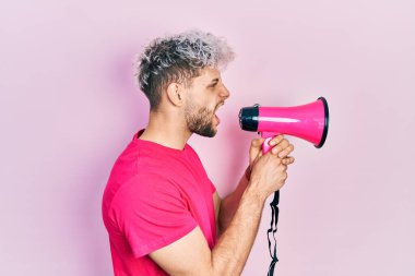 Pembe arka planda megafonla bağıran İspanyol genç adam.