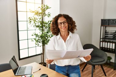 Ofiste çalışırken gülümseyen orta yaşlı İspanyol kadın.