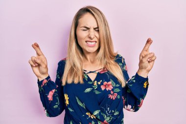 Sıradan kıyafetler giyen, umut ve gözlerin kapalı bir şekilde gülümseyerek el hareketi yapan beyaz bir kadın. Şans ve batıl inançlar. 