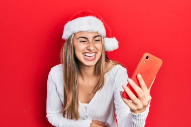 Güzel İspanyol kadın yılbaşı şapkası takıyor akıllı telefon kullanıyor ve kahkahalarla gülüyor çünkü komik çılgın bir şaka.. 