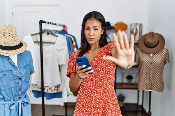 Young Hispanic Woman Working Retail Boutique Using Smartphone Doing Stop — Stockfoto