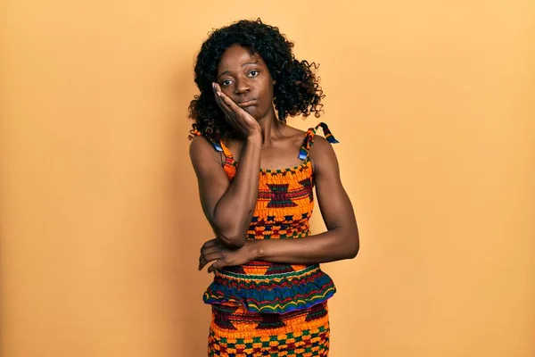 伝統的なアフリカの服を着ている若いアフリカ系アメリカ人女性は 両腕を組んでうつ病の問題に疲れて退屈しているように見える — ストック写真