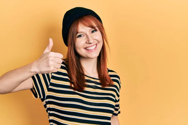 Kızıl Saçlı Yün Şapkalı Genç Kadın Mutlu Pozitif Gülümsüyor Başparmağıyla — Stok fotoğraf