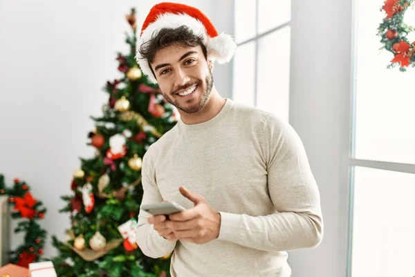 Νεαρός Ισπανός Που Φοράει Χριστουγεννιάτικο Καπέλο Χρησιμοποιώντας Smartphone Στο Σπίτι — Φωτογραφία Αρχείου