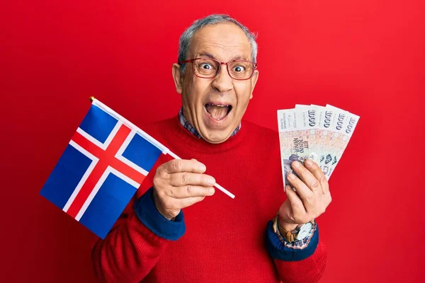 英俊的老年男子 头戴白发 手持冰原旗 头戴冰岛克朗钞票 惊喜交集 睁大眼睛惊呼 庆祝胜利 — 图库照片