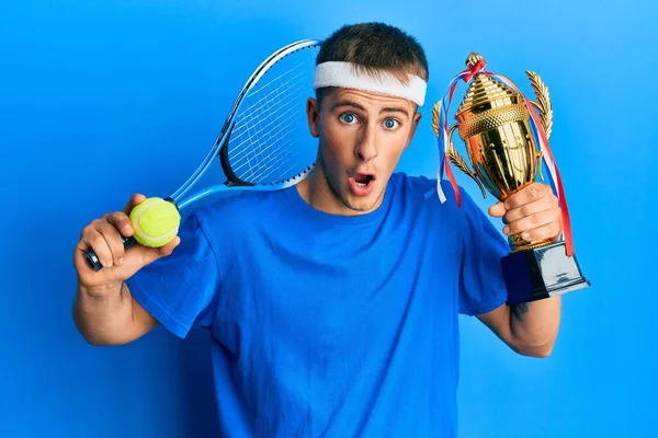 Young Caucasian Man Playing Tennis Holding Trophy Afraid Shocked Surprise — Stock Photo, Image