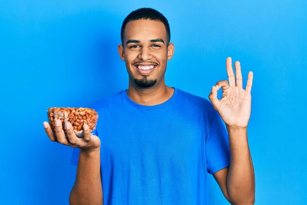 Joven Afroamericano Hombre Sosteniendo Tazón Cacahuetes Haciendo Signo Con Los — Foto de Stock