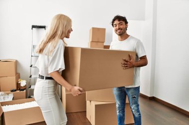 Genç ve güzel bir çift mutlu bir şekilde gülümsüyor. Yeni evlerinde büyük bir karton kutu tutuyorlar..