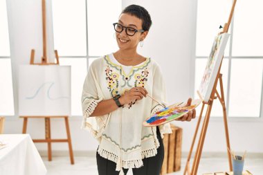 Genç İspanyol kadın resim stüdyosunda kendine güvenen gülümsüyor.