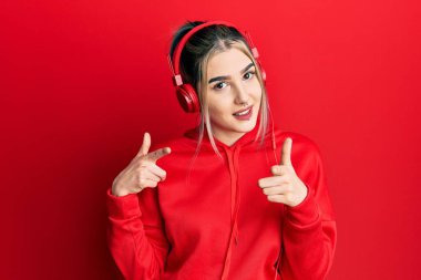 Spor kıyafetleri giyen, kulaklık takan, kameraya mutlu ve komik yüzlü genç bir kız. iyi enerji ve titreşimler. 