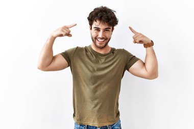 Hispanic man standing over isolated white background smiling pointing to head with both hands finger, great idea or thought, good memory 