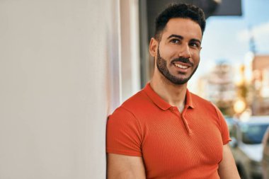 Genç İspanyol adam gülümseyerek şehirde mutlu mesut dikiliyor..