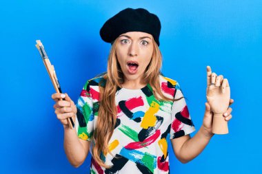 Beyaz kadın sanatçı elinde küçük ahşap manikür ve boya fırçaları tutuyordu. Korkuyordu ve şok olmuştu.. 