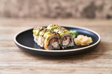  Ahşap bir yüzeyde karides ve peynir kremalı uramaki suşi tabağı.