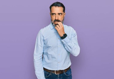 Orta yaşlı, sakallı, iş gömleği giyen, gergin ve elleri ağızdan tırnak yiyen bir adam. anksiyete. 