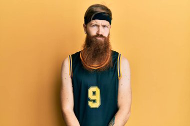 Uzun sakallı, basketbol üniforması giyen, kederli, sinirli ve korkmuş bir kızıl saçlı adam. hüzünlü ifade. 