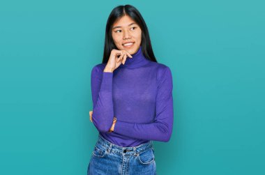 Güzel, genç Asyalı bir kadın gündelik kıyafetler giyip kameraya bakıyor. Kollarını kavuşturup gülümsüyor ve çenesini kaldırıyor. Olumlu düşünmek. 