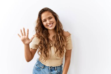 Güzel İspanyol kadın tek başına ayakta dikilirken arka plan beş numarayı gösterip işaret ederken kendinden emin ve mutlu bir şekilde gülümsüyor.. 