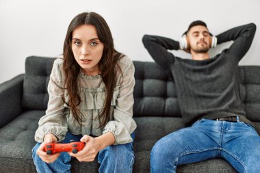 Genç İspanyol çift video oyunu oynuyor ve evde müzik dinliyor..