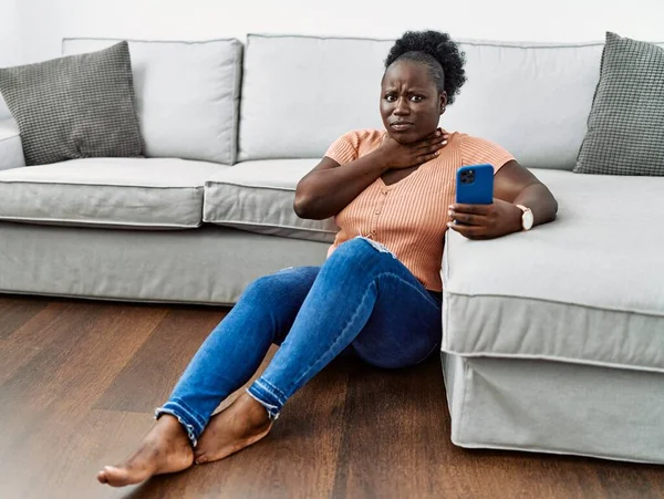 Ung Afrikansk Kvinna Med Smartphone Sitter Golvet Hemma Skära Halsen — Stockfoto