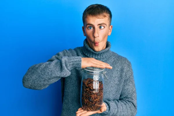 Young Caucasian Man Holding Jar Raisins Making Fish Face Mouth — Fotografia de Stock