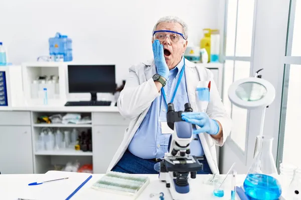 科学研究所で働いているシニア白人男性は恐れてショックを受け 驚きと驚きの表情で手で顔 — ストック写真