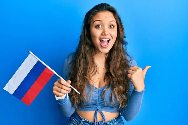 Mladá Hispánka Drží Ruskou Vlajku Ukazující Palcem Nahoru Stranu Usmívá — Stock fotografie